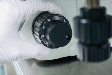 hand wear white glove turn scale adjusting focus of microscope