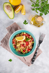  Salmon salad with tomatoes, avocado and quinoa in a blue bowl on a light gray table top view, a dish of balanced nutrition. Vertical photo