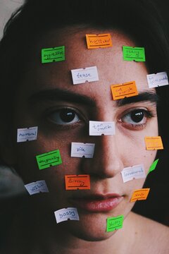 Closeup portrait of young woman with price tags on face with texts as stereotype social norms / taboos / labels / gender roles, an artistic image about womens rights
