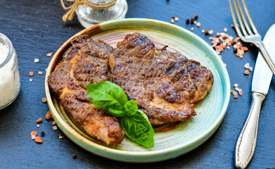 Grilled juicy pork steak, BBQ dishes on black background with copy space. Top view, flat lay food