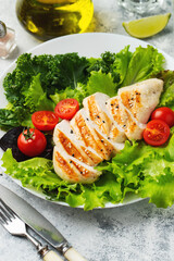 Chicken breast fillet and vegetable salad with tomatoes and green leaves on a light background. The concept of healthy food and keto diet