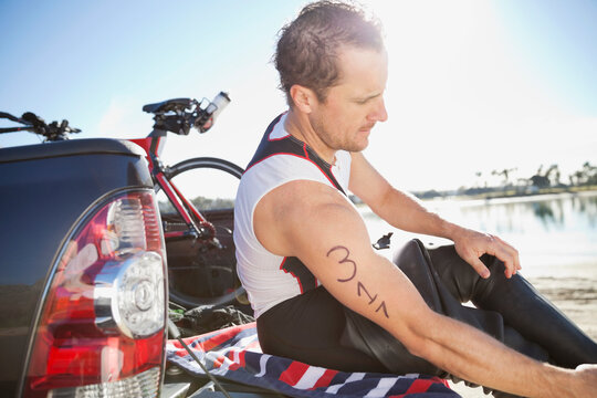 Side View Of Triathlete Sitting On Tailgate Of Pick Up Truck