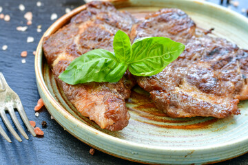 Grilled juicy pork steak, BBQ dishes on black background with copy space. Top view, flat lay food