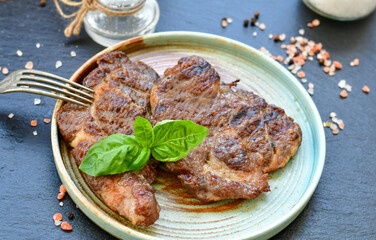 Grilled juicy pork steak, BBQ dishes on black background with copy space. Top view, flat lay food