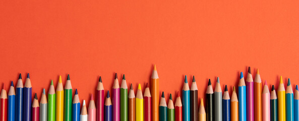 Colored pencils isolated on red background close up concept with copy space for text