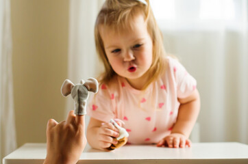 Little expressive girl and his brother playing theater with animal finger puppets. Role-playing games and activities  to improve language skills, creativity, social awareness, emotional development