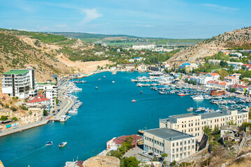 Obraz premium Balaklava bay summer in sunny weather. Crimea, Russia. Genoese fortress Chembalo. A lot of boats and ships. mountains