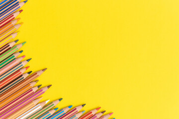 Fototapeta premium Colored pencils isolated on yellow background close up concept with copy space for text 