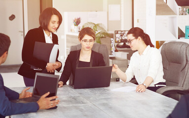 Three young successful business women in the office, together, happily working on a project