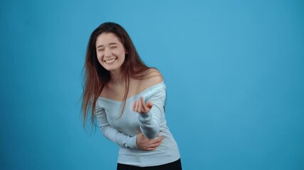 The portrait of a young woman amused by the situation who laughs with her mouth to her ears with her hand on her belly and with the index finger indicated before. Asian with dark hair, dressed in a