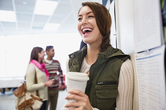 Smiling Female Student With Coffee Standing In College Campus