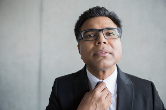 Portrait Businessman With Black Hair Adjusting Tie