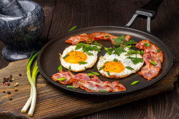 fried eggs with bacon and herbs in a frying pan