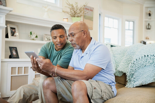 Son helping senior father to use digital tablet