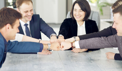 Unity and teamwork concept of young business people folding their hands together