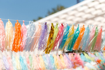 Multicolored garlands fringe with tassels on a summer beach playground. Summer background
