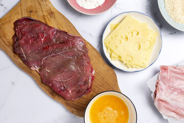 Preparation of traditional Milanese escalope with flour, egg, breadcrumbs, cheese and ham