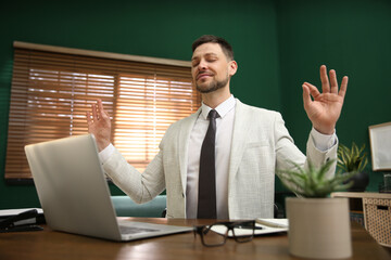 Calm businessman meditating at desk in office