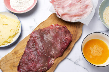 Preparation of traditional Milanese escalope with flour, egg, breadcrumbs, cheese and ham