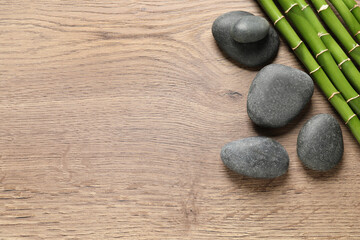 Obraz na płótnie Canvas Spa stones and bamboo stems on wooden table, flat lay. Space for text