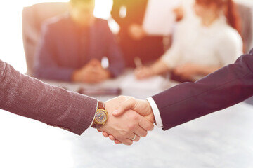 Business people shaking hands finishing a meeting in the background of their work team