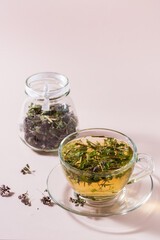 Fresh hot tea with oregano in a cup and dry herb in a jar. Herbal medicine and alternative therapy. Vertical view