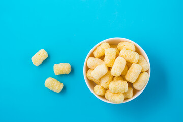 Corn sticks in powdered sugar in a bowl on a blue background. Top view