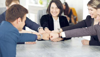 Unity and teamwork concept of young business people folding their hands together