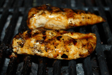 Close-up of chicken breast cooking on a barbecue grill.