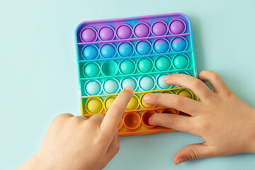 Child playing with rainbow pop it,pressing the bubbles with his fingers,top view.New antistress toy for children and adult.Copy space for text or design.