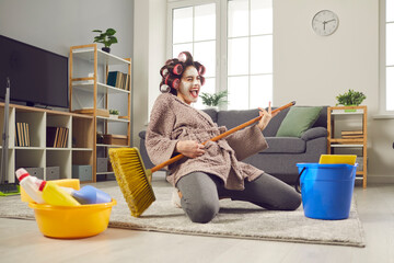 Funny housewife who cleans the house, sings and plays on a broom, as if on an imaginary guitar....