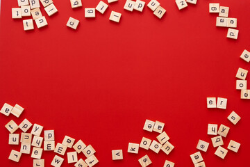 Background image The letters are scattered in disarray. English letters. wooden square letters on bright red background. Greeting card, ready-made layout, selective focus.