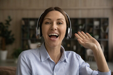 Hi everyone. Portrait of active teen female presenter in headphones look at camera greet gen z...