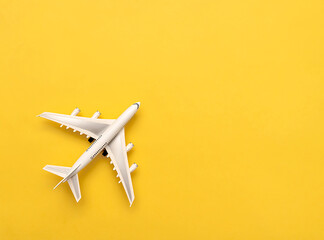 The white plane lies on a yellow background. Travel concept.