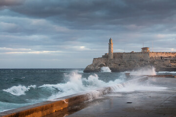 Big waves on Malecon streets during sunrise with storm clouds in background. Havana, Cuba