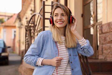 Fototapeta premium Happy young woman with headphones listening to music on city street
