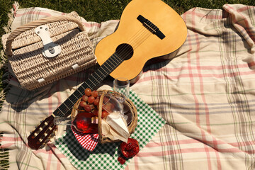 Picnic basket with delicious food and guitar on blanket, flat lay. Space for text