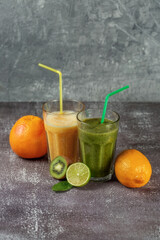 Fototapeta na wymiar Two tall glasses of orange juice and a banana-orange kiwi and spinach smoothie