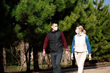 Young European man and woman in protective disposable medical mask walking outdoors afraid of dangerous NCoV 2019 influenza coronavirus mutated and spreading in China