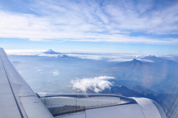 Fototapeta na wymiar view of several snow-capped volcanoes in the ecuadorian andes through the window of an airplane, clouds and the turbine of the plane can be seen.