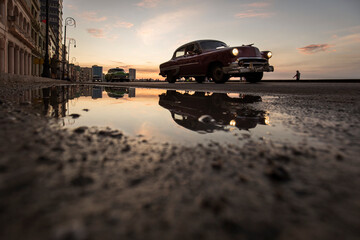 Old car on Malecon street of Havana with colourful sunset in background. Cuba