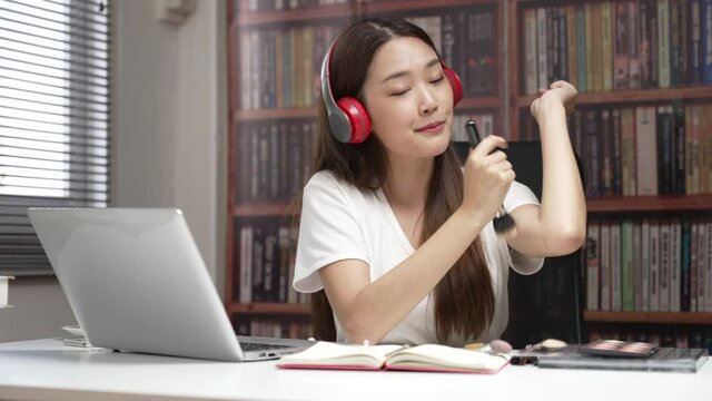 Asian Woman making video live tutorial for her cosmetics blog. Cosmetic reviewer. Medium close up shot of young lady talking on cosmetics while holding a brush on and demonstrate during record video. 