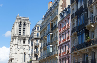 Fototapeta na wymiar Traditional facades of French houses with typical balconies and windows with Notre Dame cathedral towers in the background. Paris.