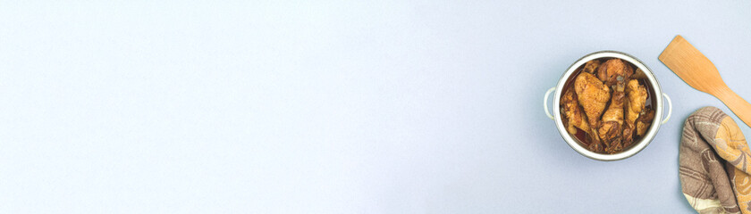 Wide banner kitchen background with saucepan and roasted chicken, towerl and wooden spoon, top view and flat lay background with copy space