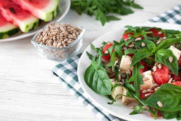 A portion of fresh delicious salad with watermelon, feta cheese, basil leaves, arugula and peeled Sunflower seeds. Close-up.