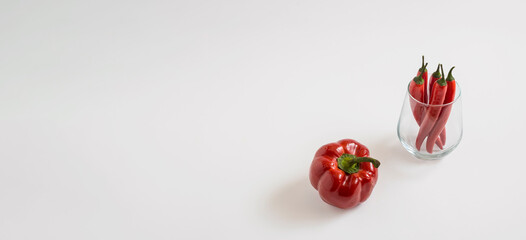 Paprika, red chili peppers in a transparent glass on a white background, banner compopsition with a copy space