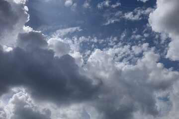 Blue sky with clouds. Spring or summer background. 
White clouds on the blue sky have a complex pattern.
