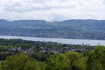 Fototapeta na wymiar Landscape with mountains in the background and part of Lake Zurich seen from wooden lookout named Loorenkopfturm (Loorenkopf tower). Photo taken May 18th, 2021, Zurich, Switzerland.