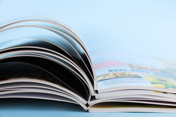 Stack of magazines on light blue background, closeup