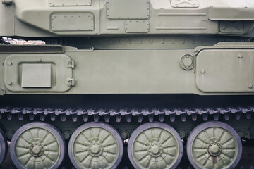 Side part of modern military combat equipment. Wheels and tracks of the tank.